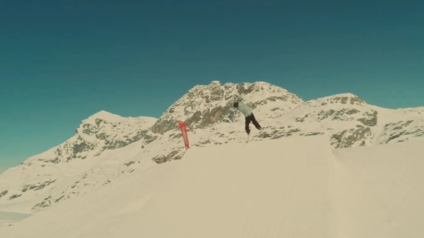 A skier in the air in the Corvatsch snow park, with the mountain behind