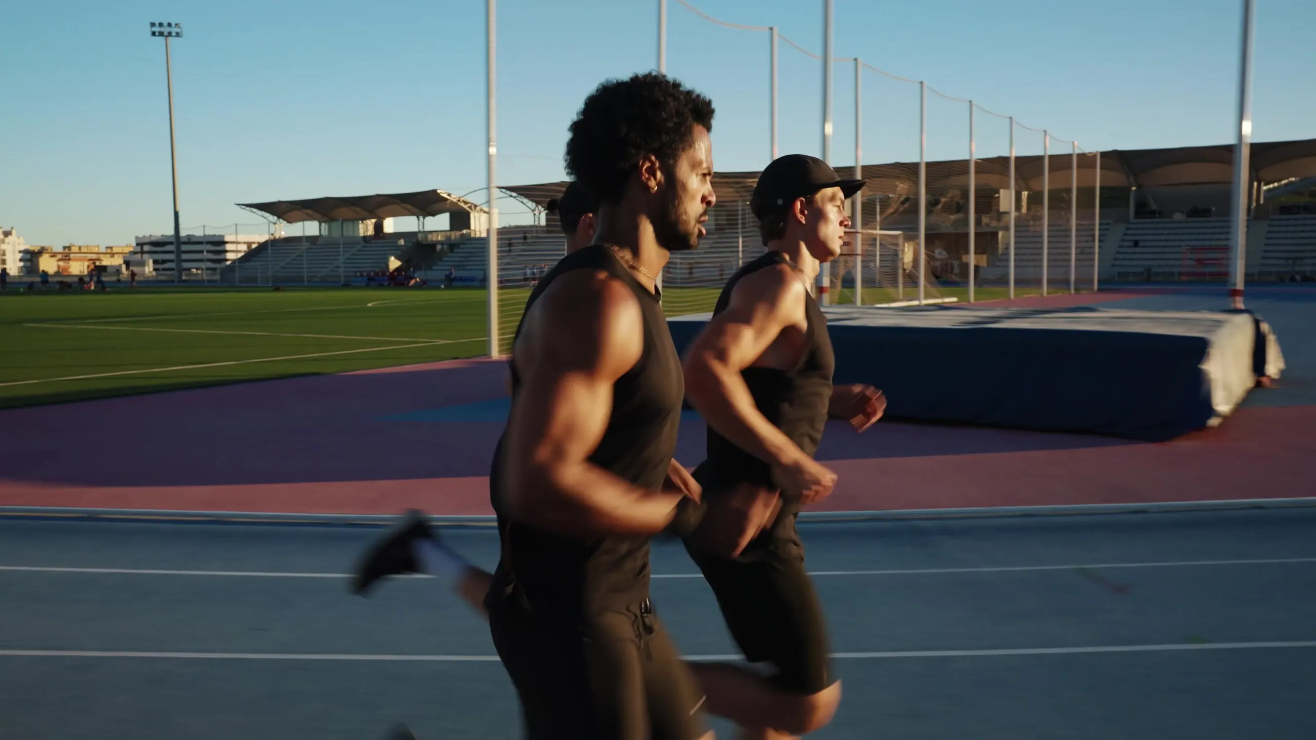 Three runners on the athletics track in Estepona in low evening sun